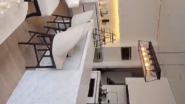 Una cocina moderna con una isla central, una zona de comedor con mobiliario blanco y una lámpara colgante.