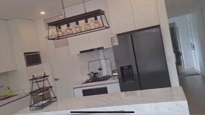 Una cocina moderna con un refrigerador de acero inoxidable, una lámpara colgante y una encimera de mármol.
