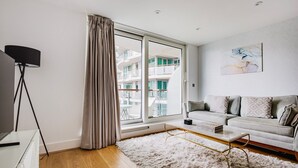 A modern living room with a sofa, a coffee table, and a large window with curtains.