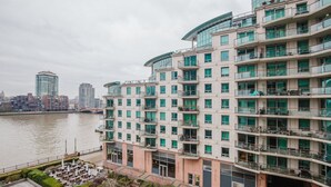 A multi-story hotel with balconies, a river view, and a modern architectural design.