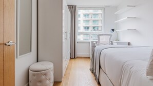 A modern bedroom with a bed, a desk, and a chair.