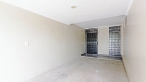 A room with a concrete floor, a white ceiling, and a door with a metal grid. - Citi Serviced Apartments - Gaba Place (Port Moresby)