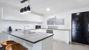 A modern kitchen with white cabinets, a black countertop, and a black door. - Citi Serviced Apartments - Gaba Place (Port Moresby)