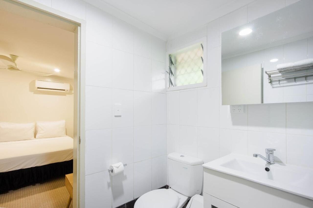 Casa de banho de hotel com sanita, lavatório e espelho sobre o lavatório.