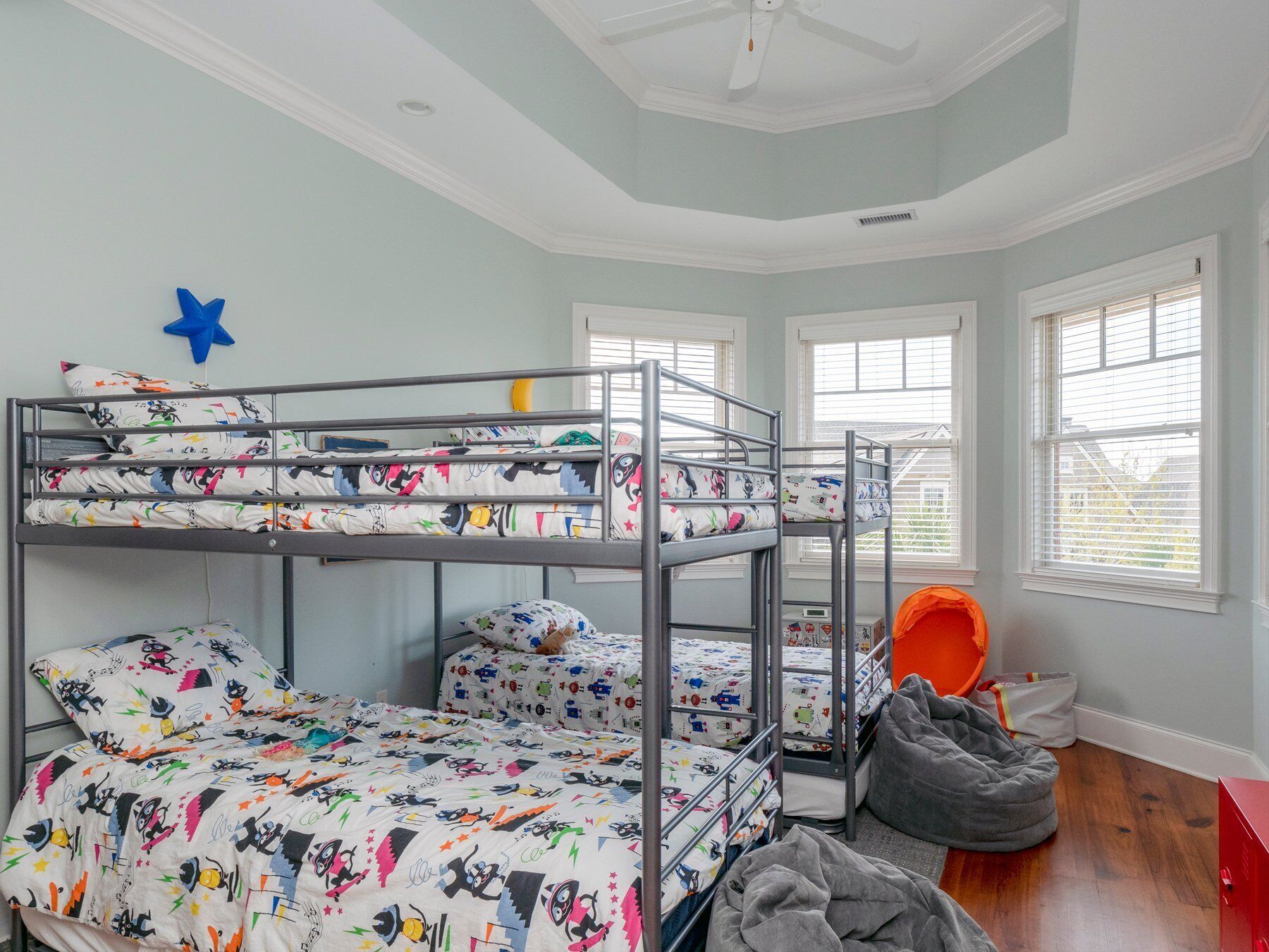 Een slaapkamer met een stapelbed, sterrenversiering, een relaxfauteuil en een rode kast.