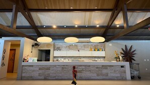 Een receptiezone met een stenen balie, houten balken in het plafond en hangende lampen.