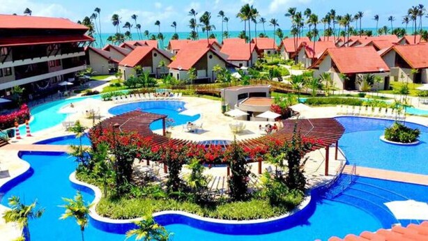 Een resort met diverse bungalowachtige accommodaties, een centraal gelegen zwembad en uitzicht op de oceaan.