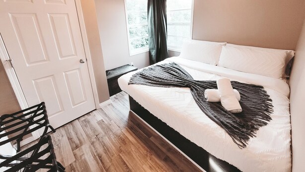 Une chambre à coucher avec un lit, une chaise, une fenêtre avec des rideaux et une porte.