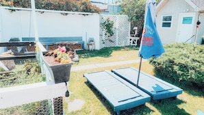 Un espace jardin aménagé avec un parterre surélevé, une petite table et un drapeau.