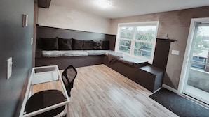 Un espace de vie compact comprenant un banc intégré le long du mur, une petite table et une chaise.