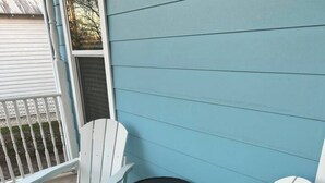 Two Adirondack chairs with teal cushions on a concrete patio against a blue wall. - The Azure Charm — Amazing 3BR 2BA Home 1 Mile to Fort Sam Houston & The Pearl (San Antonio)