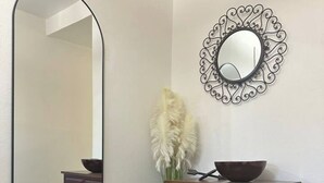 A room with a dark wooden cabinet, a large mirror, and a decorative wall piece. - The Azure Charm — Amazing 3BR 2BA Home 1 Mile to Fort Sam Houston & The Pearl (San Antonio)