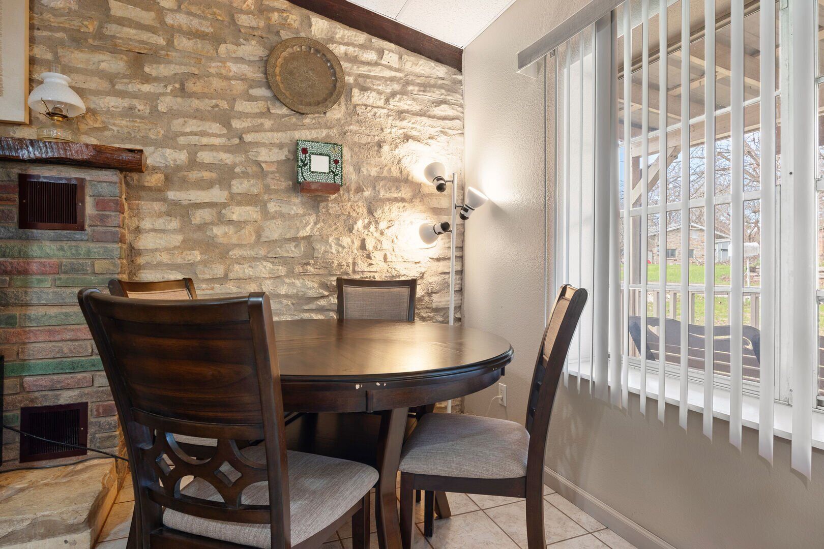 A dining area with a stone wall, a round wooden table, and four chairs.