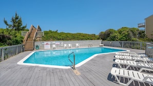 A swimming pool with a wooden deck, lounge chairs, and a staircase leading to a deck area. - Sea Rose: Oceanfront Condo, Great Ocean Views, Community Pool (Nags Head)