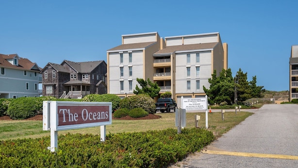 A multi-story residential building with a sign reading "The Oceans." - Sea Rose: Oceanfront Condo, Great Ocean Views, Community Pool (Nags Head)