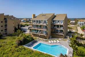 A multi-story hotel with a swimming pool, balconies, and outdoor seating areas.