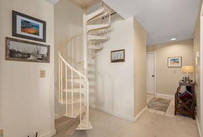 A staircase leading to a landing with a door, a small table with a lamp, and framed pictures on the walls.