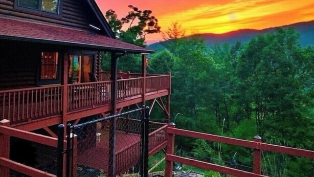 Una cabana de fusta amb un balcó que dona a un paisatge forestal al capvespre.