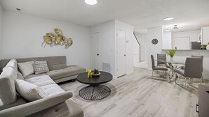 A modern living room with a grey sofa, a round coffee table, and a dining area with a glass table and chairs. - 13 Minutes from Downtown Raleigh  (Raleigh)