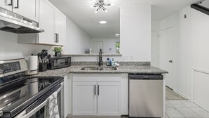 A modern kitchen with white cabinets, a stainless steel sink, a microwave, a stove, and a dishwasher. - 13 Minutes from Downtown Raleigh  (Raleigh)