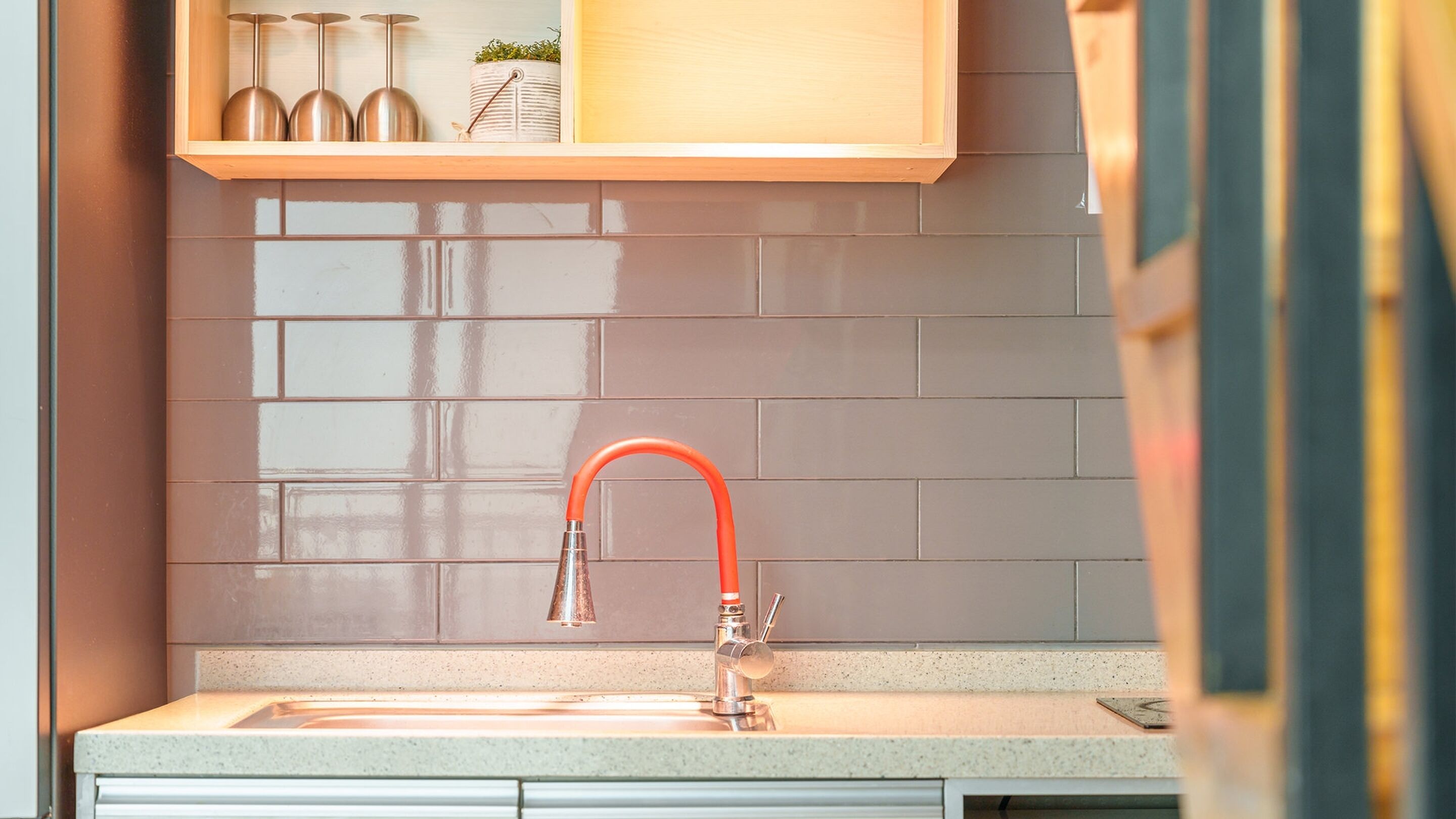 A kitchen with a modern faucet, a countertop, and a backsplash.