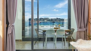 A balcony with a table and chairs, overlooking a coastal area with a view of the sea and a bridge. - Yeosu Porrr Ocean View Pension (Yeosu)
