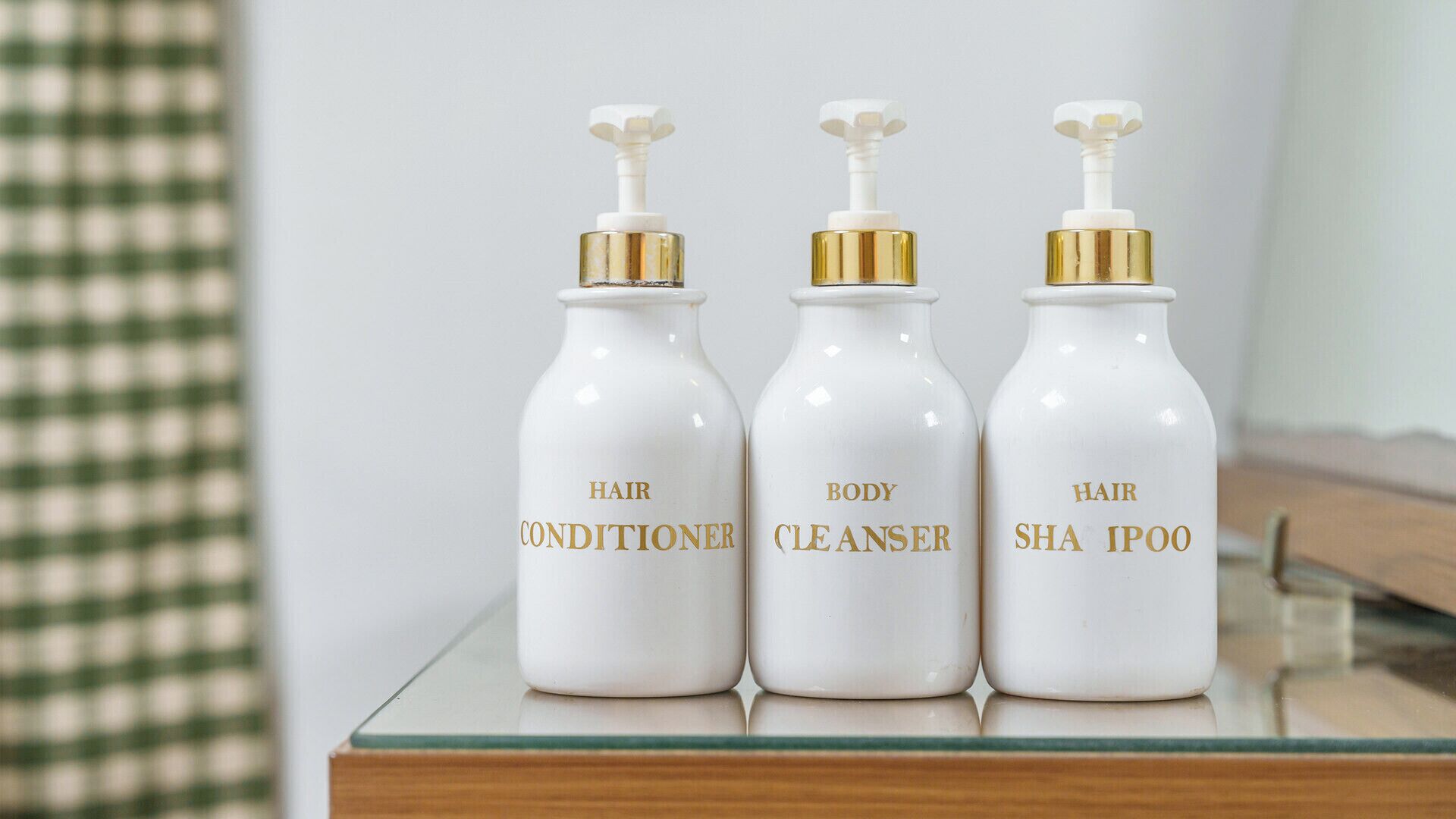Three bottles of hair care products on a reflective surface.