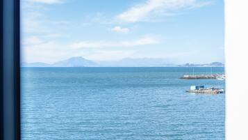 Vista de un mar tranquilo con una cadena montañosa distante y un muelle con barcos.