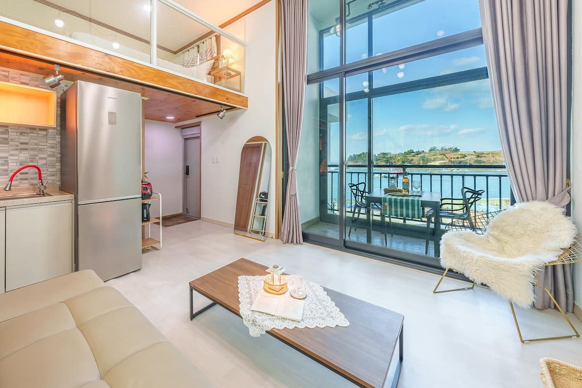 A modern apartment with a kitchen, living area, and balcony with a view.