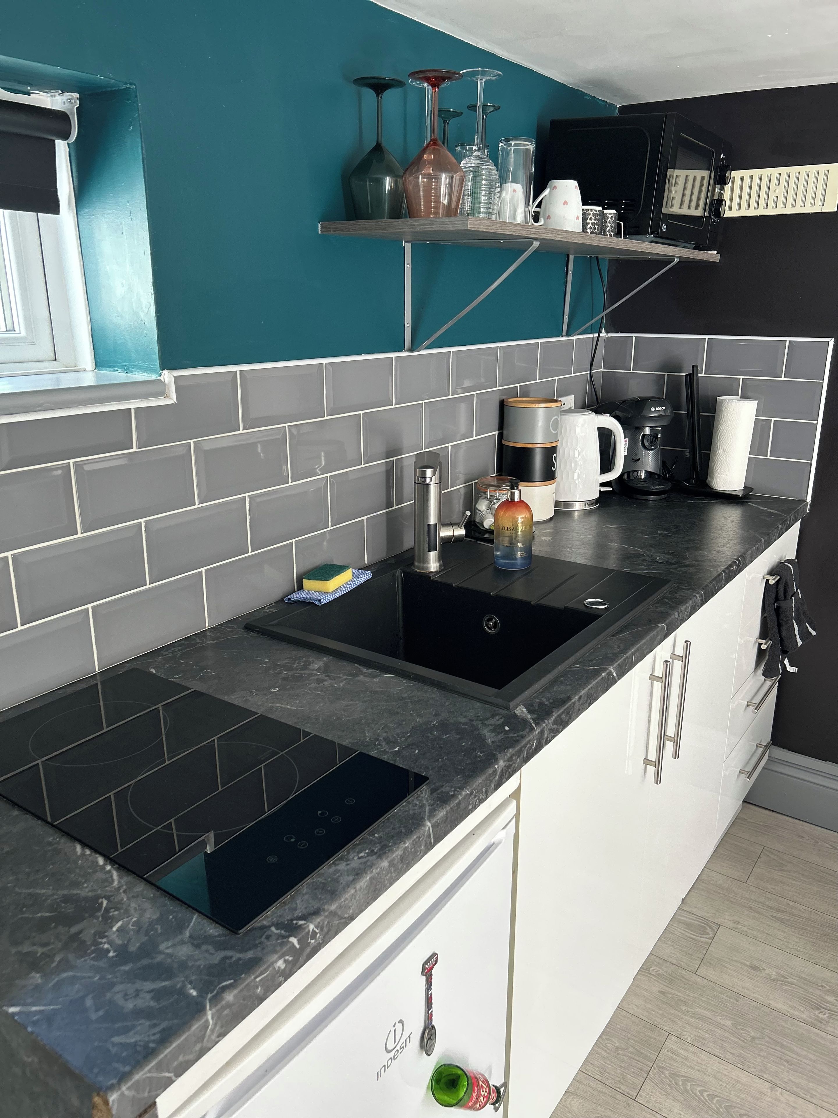 A kitchen with a black countertop, a sink, and a coffee maker.