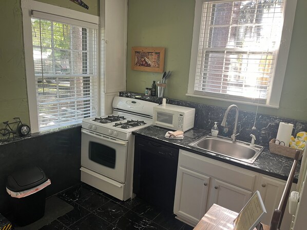 Cocina compacta con estufa a gas, microondas, lavabo y armarios.