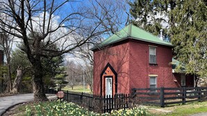A red brick building with a green roof, surrounded by a black picket fence and daffodils. - Welcome to Bourbon Oak Smokehouse, in the heart of Bardstown, KY (Bardstown)