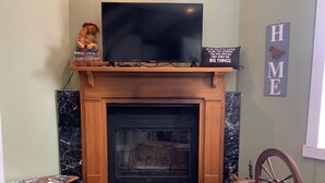 A living room with a fireplace, a television on a stand, a bookshelf, and a sign with the letters "HME". - Welcome to Bourbon Oak Smokehouse, in the heart of Bardstown, KY (Bardstown)