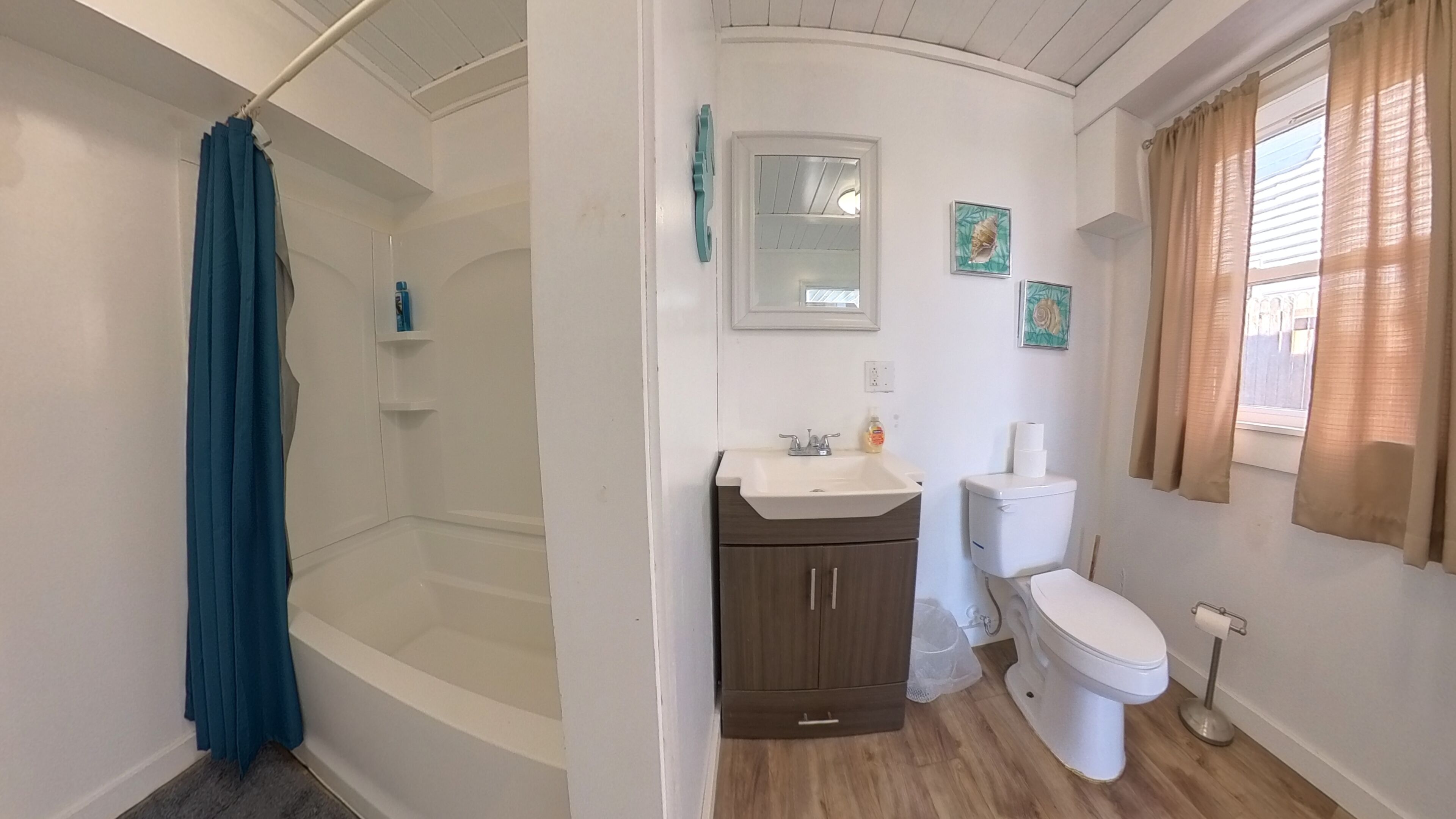 A bathroom with a bathtub, toilet, sink, and shower curtain.