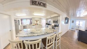 A kitchen with a large island, white cabinets, stainless steel appliances, and a sign that says "BEACH". - Oceanfront, Central, Huge 5k sq ft Home w Huge Private Pool, Hot tub, & Gameroom (North Myrtle Beach)