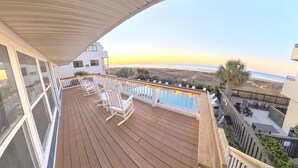 A wooden deck with white rocking chairs and a pool, overlooking a beach and ocean. - Oceanfront, Central, Huge 5k sq ft Home w Huge Private Pool, Hot tub, & Gameroom (North Myrtle Beach)