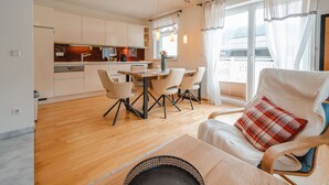A modern living room with a dining area, a kitchen, and a balcony with a view. - Lovely apartment for 3 guests with TV and terrace (Bad Hofgastein)
