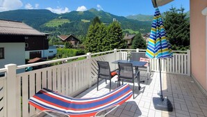 A balcony with a view of mountains, a striped hammock, and a table with chairs. - Lovely apartment for 3 guests with TV and terrace (Bad Hofgastein)