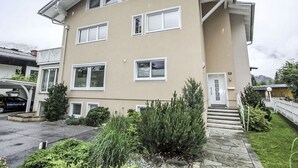 A two-story building with multiple windows, a front door, and a small garden area with various plants. - Lovely apartment for 3 guests with TV and terrace (Bad Hofgastein)