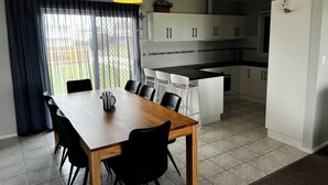 Una cocina moderna con armarios blancos, una encimera negra y un comedor con mesa de madera y sillas negras.