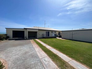 Une maison moderne dotée d’un garage, d’un patio couvert et d’une pelouse bien entretenue.