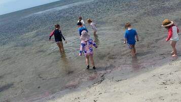 Una playa con agua cristalina y poca profundidad, y huellas en la arena.