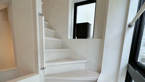 A staircase with white steps and a fire extinguisher on the landing.