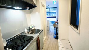 A narrow kitchen with a stove, sink, and a window.