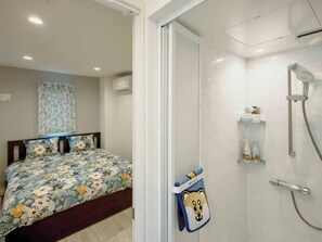 Un dormitorio con cama, ducha y toallero con una toalla.