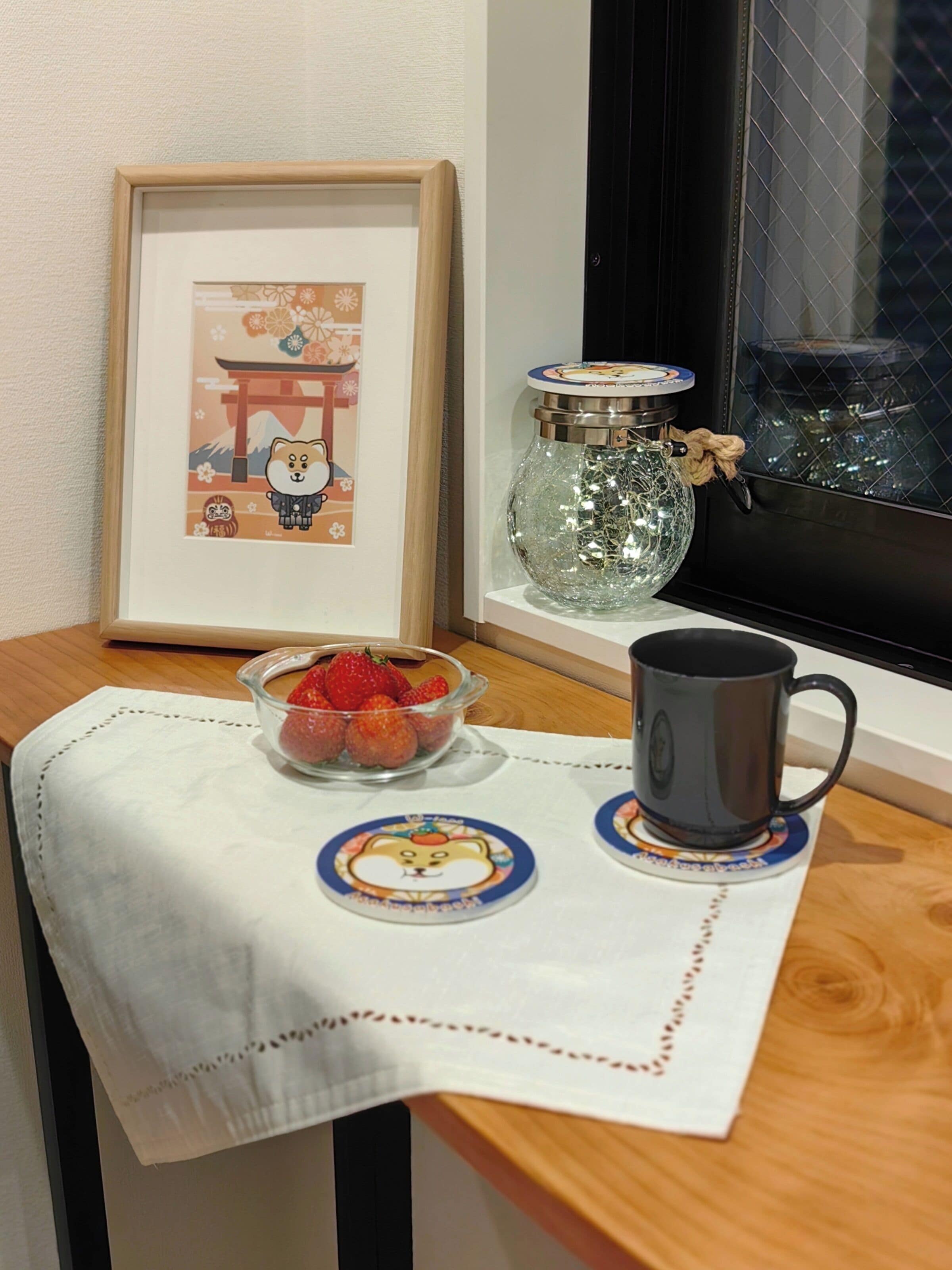 A framed picture of a bear on a shelf, a glass jar with a lid, a bowl of strawberries, and a mug on a table.