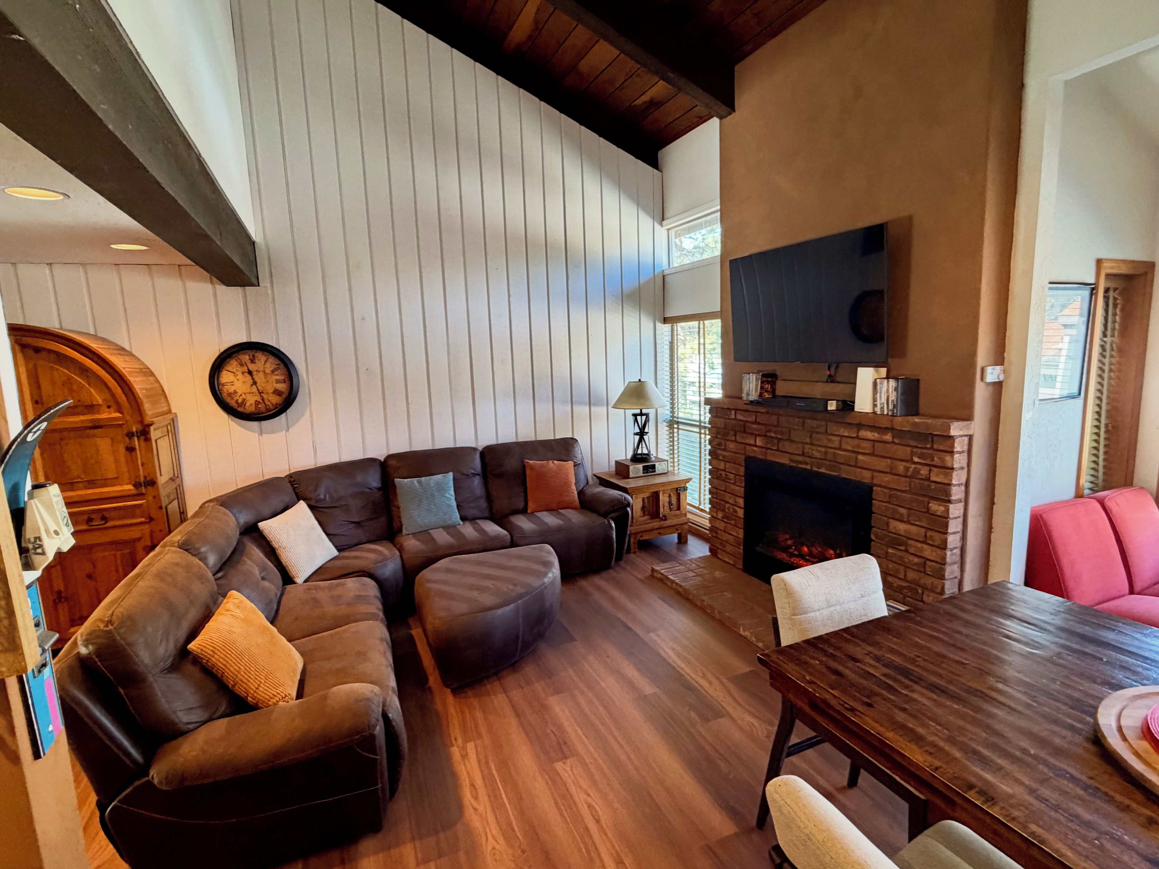 A living room with a sectional sofa, a fireplace, and a dining table.