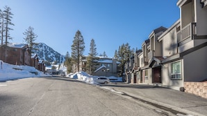 A residential street with snow-covered ground, houses with balconies, and a mountain in the background. - Slopeside Retreat at Mammoth Mountain, Ski-in\Ski-out at Canyon Lodge (Mammoth Lakes)