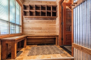 Un intérieur en bois avec un banc, un tapis à motifs et une étagère en bois dotée de crochets.