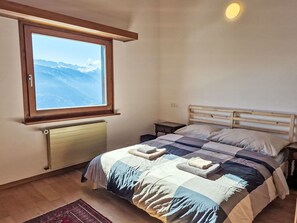 A bedroom with a bed, a nightstand, a window with a mountain view, and a radiator. - Beautiful private villa for 10 guests with WIFI, TV, terrace and panoramic view (Bluche)